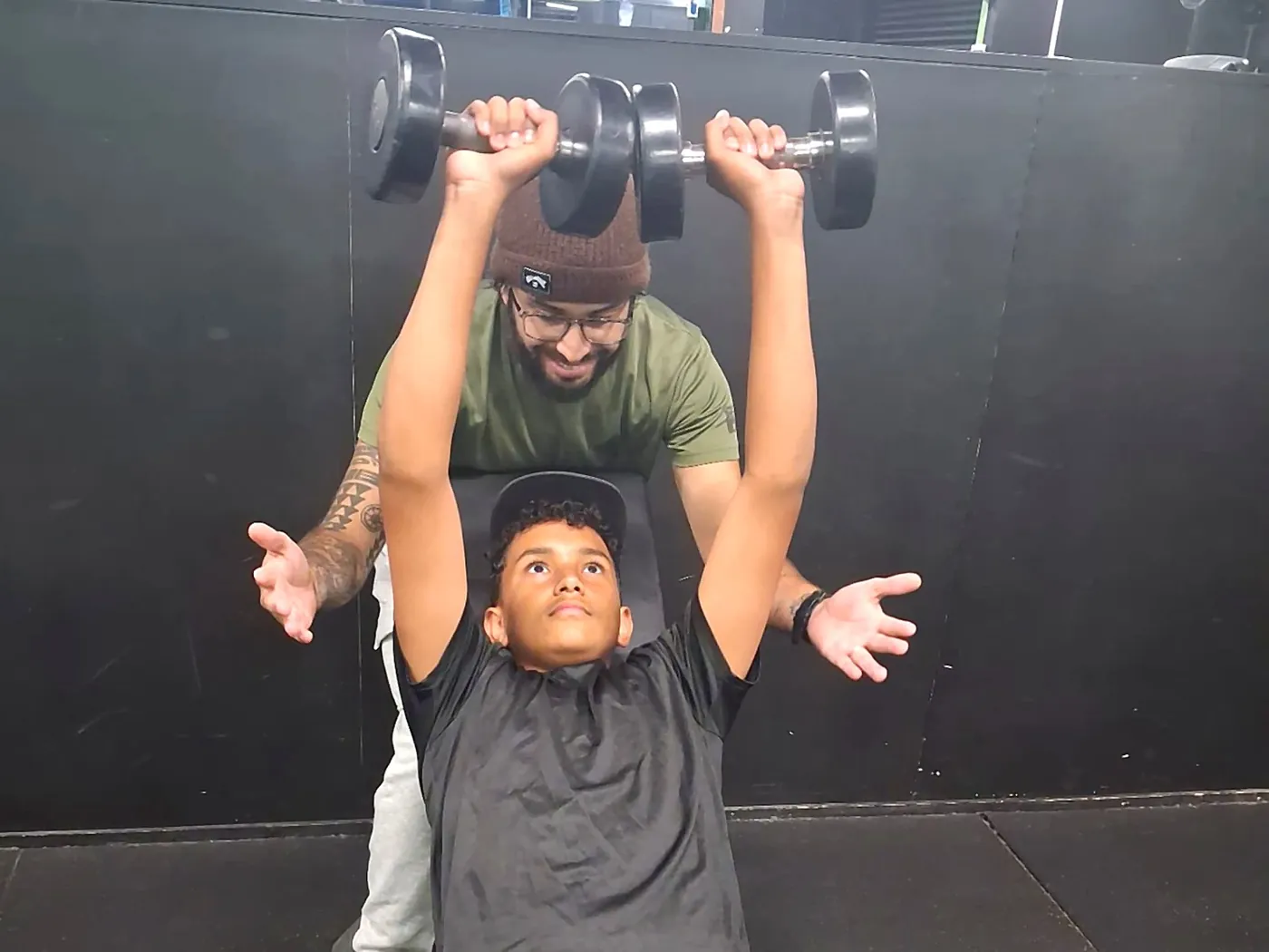 A young person strength training with support from a coach.