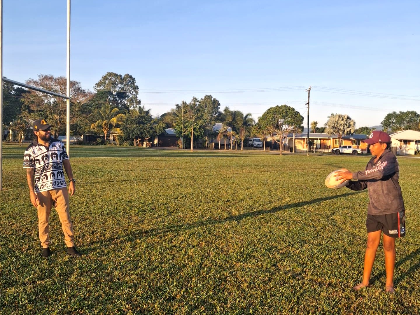 An adult and young person preparing for a rugby activity on a community field.